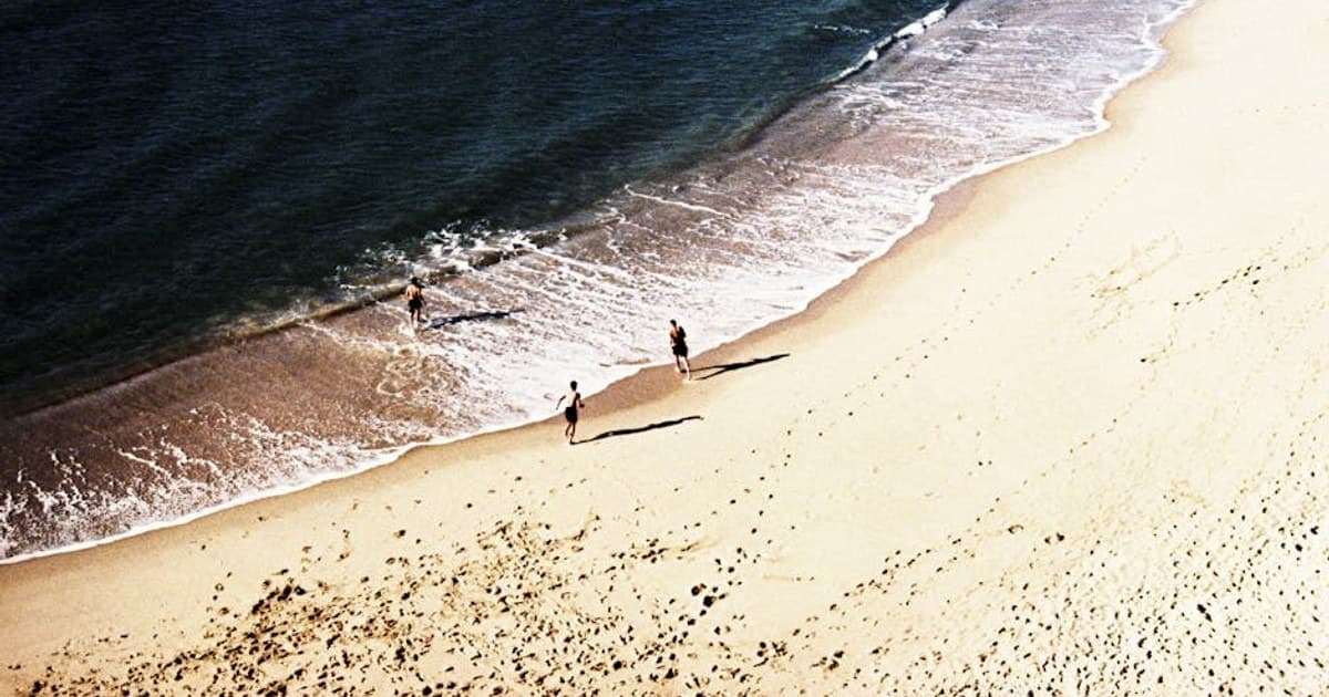 Stunning aerial view of Nazaré beach in Portugal with people enjoying the summer coastline.