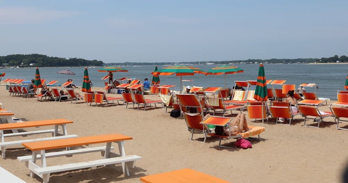 Sunny day at the beach on Shelter Island with chairs and umbrellas by the ocean.