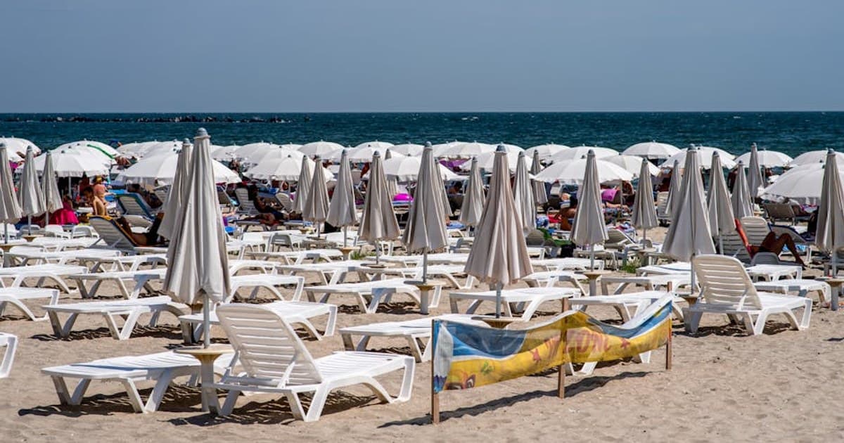A bustling Croatian beach with sun umbrellas and lounge chairs, perfect for vacation relaxation.