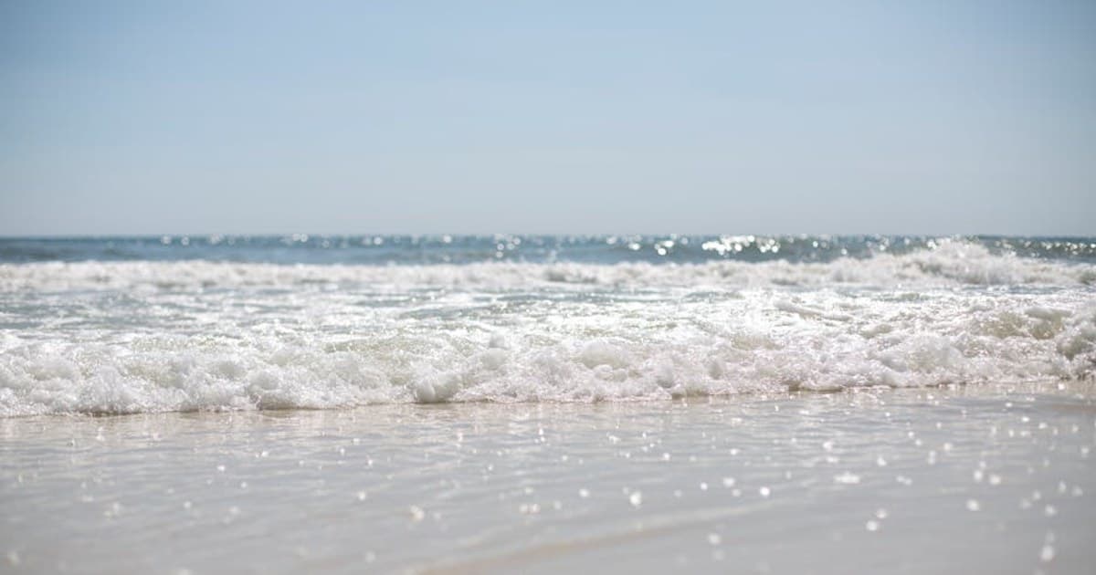 Serene beach scene with gentle waves under a clear sky, perfect for relaxation.