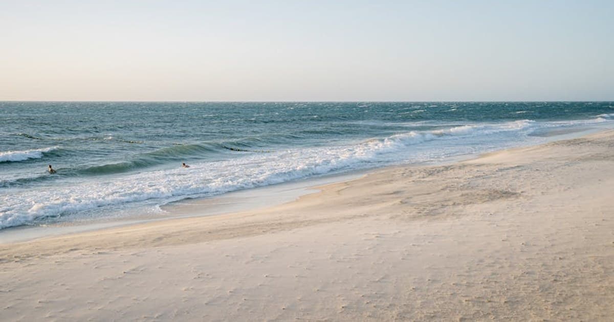 Peaceful beach scene with waves gently lapping the shore under a clear sky.