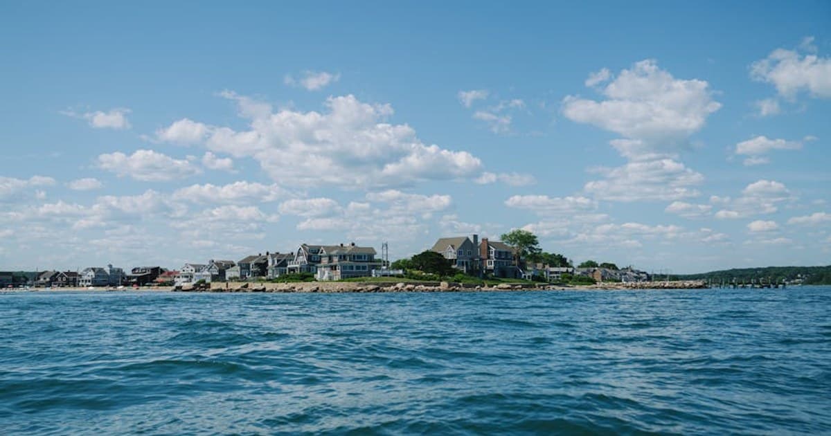 Beautiful coastal landscape featuring houses on a seashore under a blue sky.