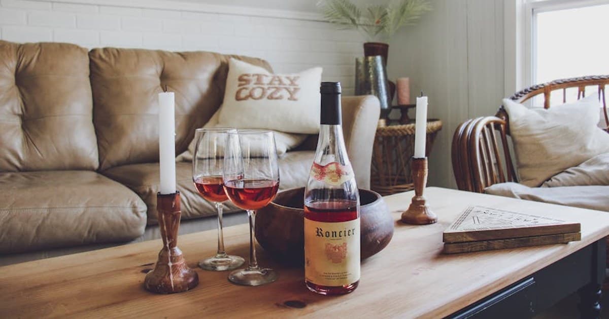 Warm and cozy living room setup with wine, candles, and a comfortable couch.