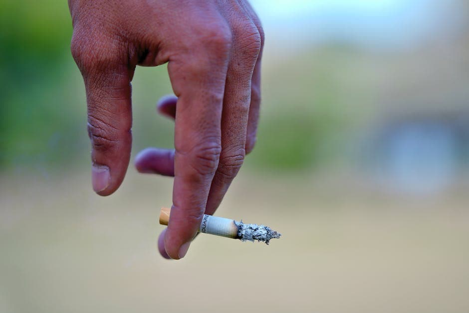 Detailed image of a hand holding a cigarette, signifying smoking habits and health risks.
