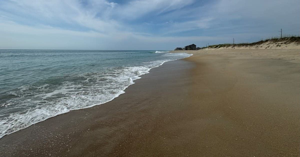 Capture the tranquility of Hatteras, NC, with a serene beach under clear skies.