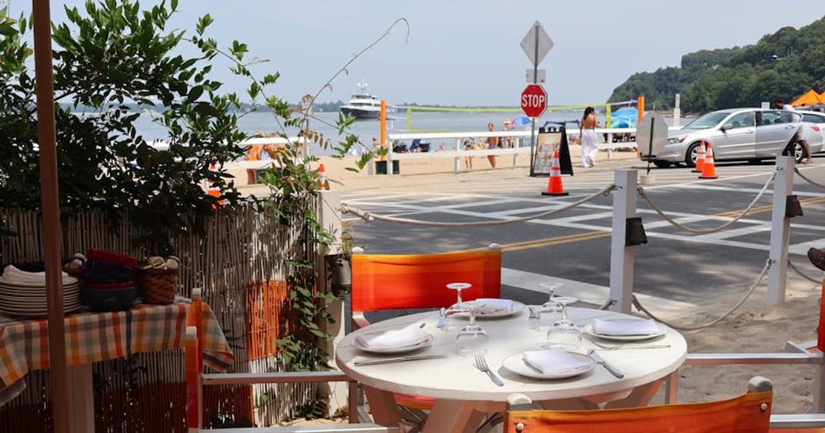 Relaxing beachside dining area with colorful chairs and set table in Shelter Island, NY.
