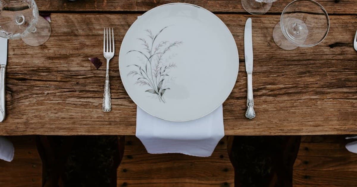 Elegant rustic table setting with vintage cutlery and floral dinnerware.