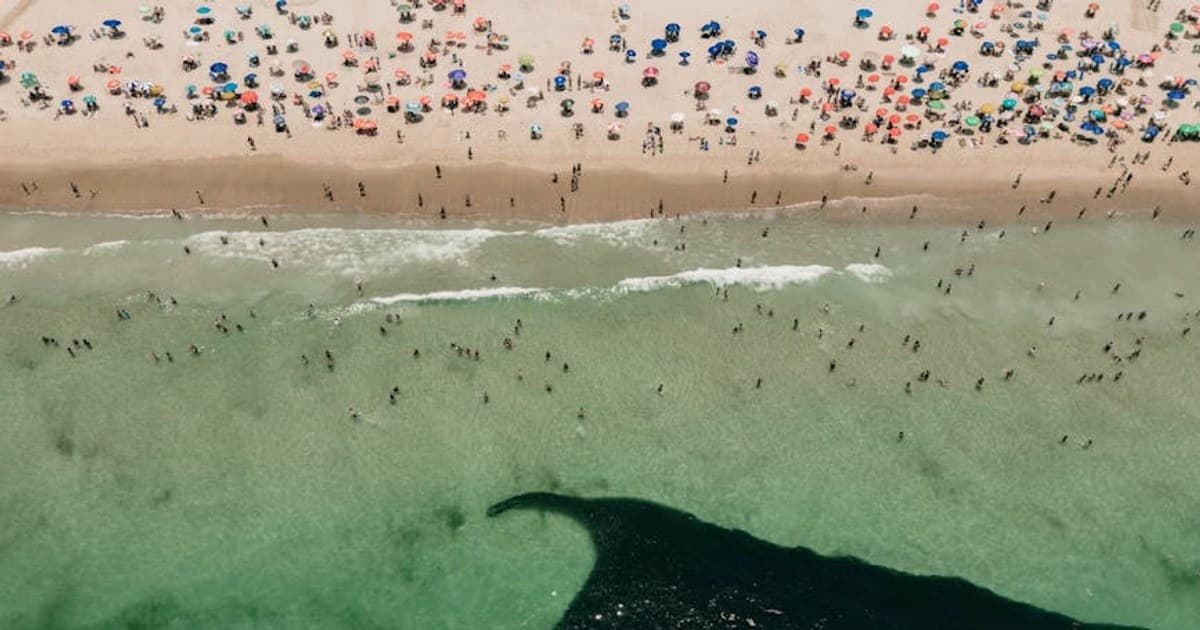 Aerial shot of a vibrant beach in Rio de Janeiro with sunbathers and colorful umbrellas.