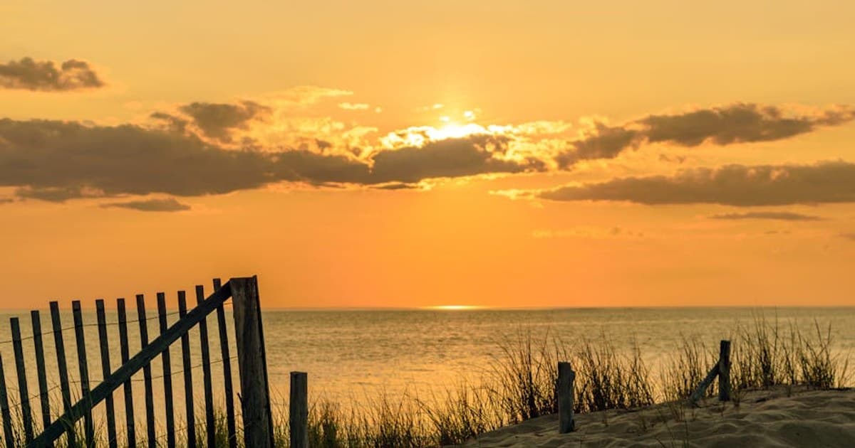 A tranquil beach scene at sunset with golden sands and calm waves, perfect for relaxation.