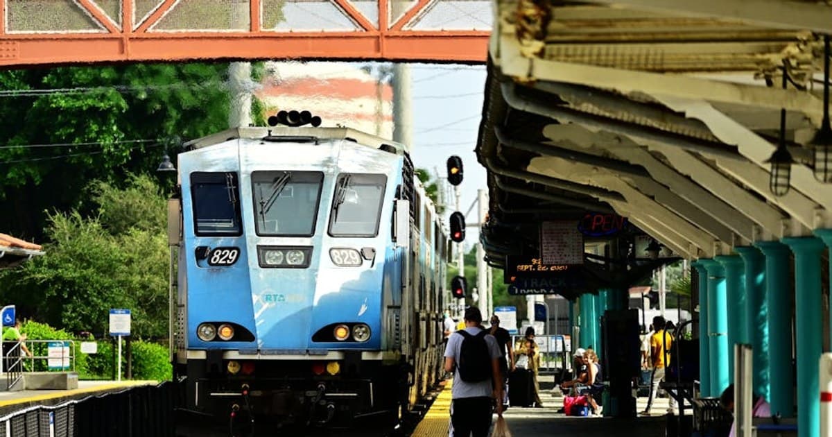Blue train approaches a bustling station, capturing daily commute life.