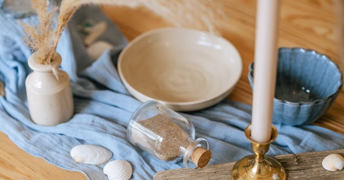 A cozy, beach-themed tablescape featuring seashells, driftwood, and soft blue textiles.