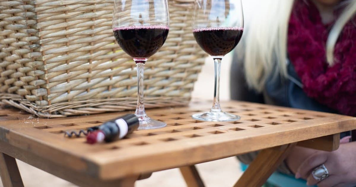Elegant red wine glasses on a wooden table during an outdoor picnic, Portugal.